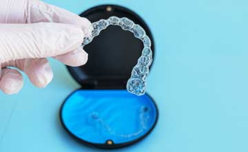 Dentist holding a clear Invisalign aligner for orthodontic treatment