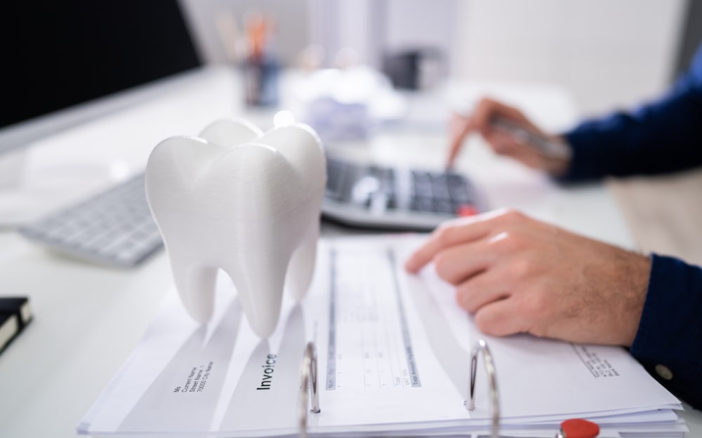 Man calculating dental implant cost in Toronto with a tooth model on the table