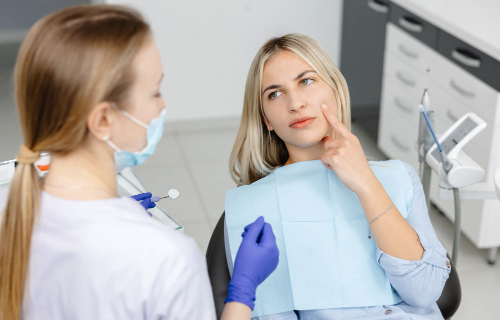 A dentist consulting with a patient while holding a dental mirror, representing treatment planning and cost discussion for root canal therapy in Canada.